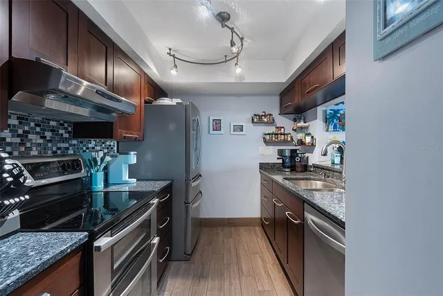 a kitchen with granite countertop stainless steel appliances and wooden cabinets