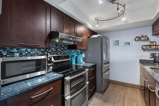 a kitchen with granite countertop stainless steel appliances and wooden cabinets