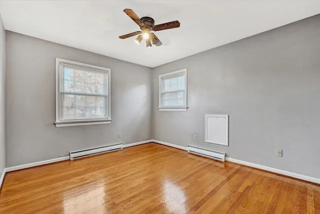 a view of an empty room with window and wooden floor