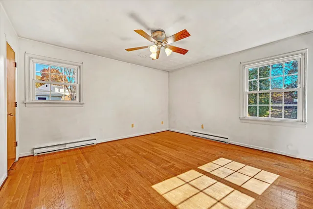 a view of empty room with wooden floor and fan