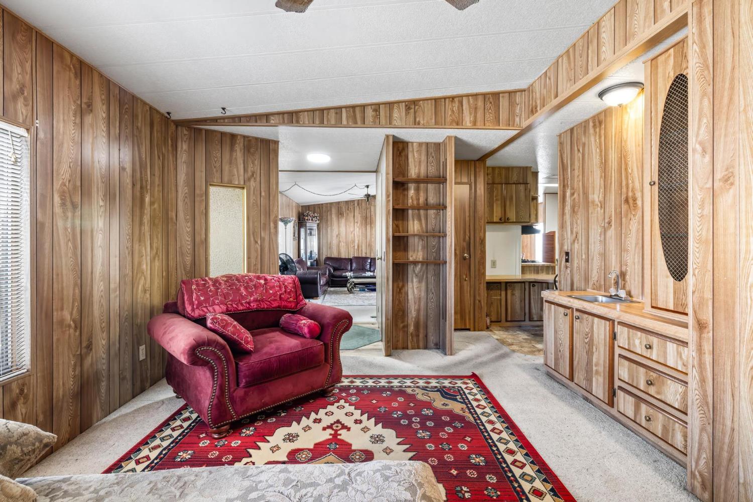 1200 South Carpenter Road, Unit 4 Modesto, CA 95351 - Photo 14 of 31 Interior space featuring wood-finish paneling throughout, light-toned carpeting, and a built-in cabinetry unit with an integrated sink