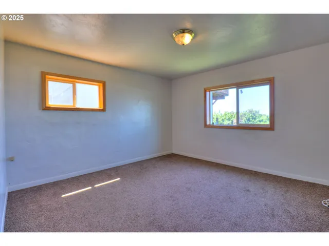 a view of a room with a large window and wooden floor