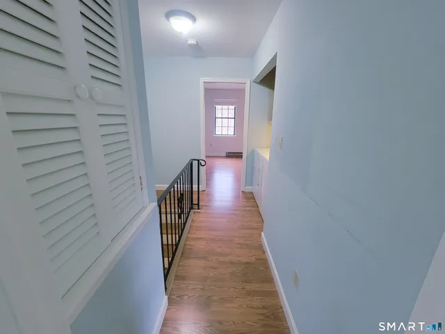 a view of a hallway with wooden floor and staircase