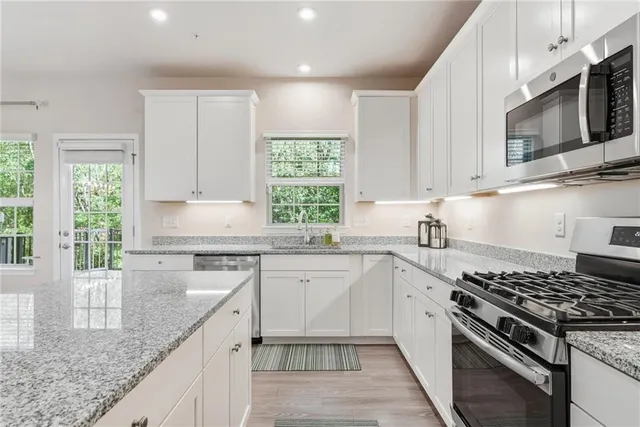 a kitchen with stainless steel appliances granite countertop white cabinets granite counter tops and a window