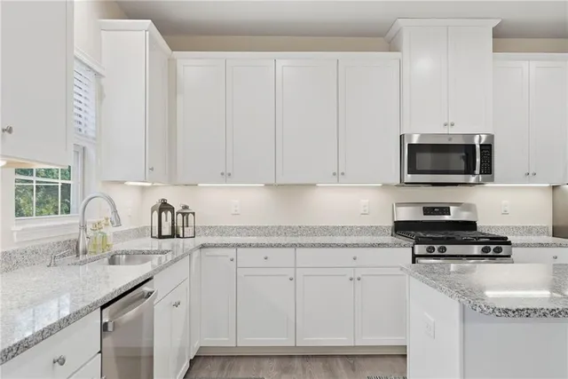 a kitchen with granite countertop white cabinets and black appliances