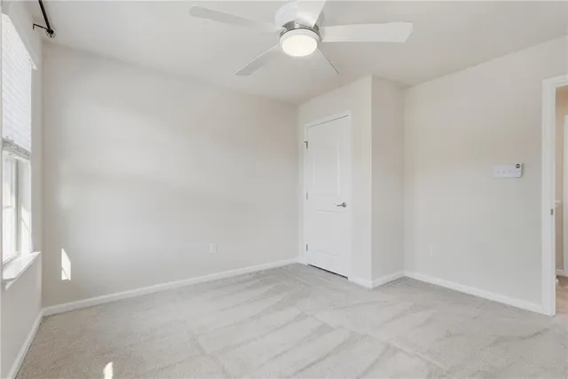an empty room with a window and a chandelier fan