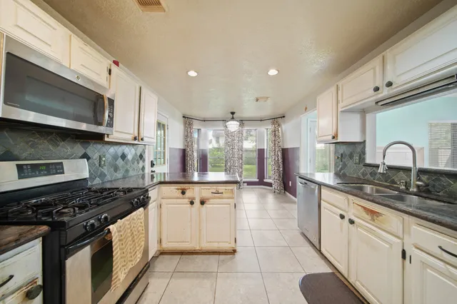 a kitchen with stainless steel appliances granite countertop a stove and a microwave