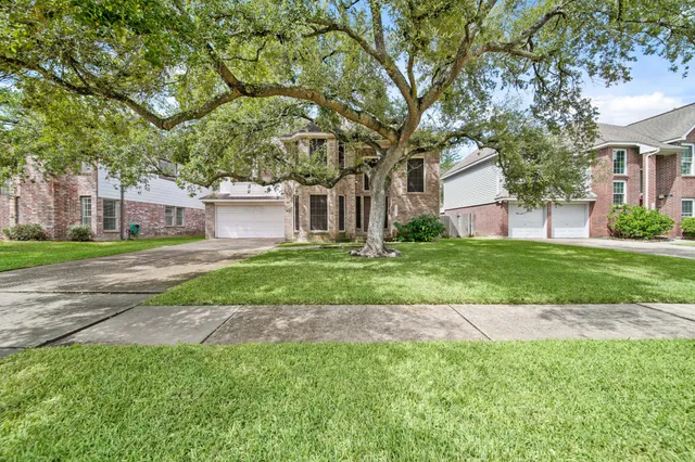a view of a house with a big yard and large trees