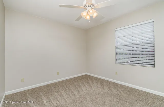 a view of an empty room and chandelier fan