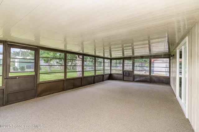 a view of an empty room with wooden floor and a ceiling fan
