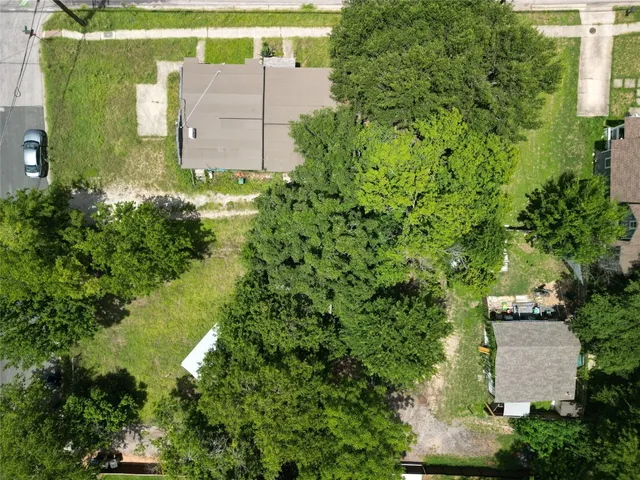 an aerial view of a house with a yard and trees all around