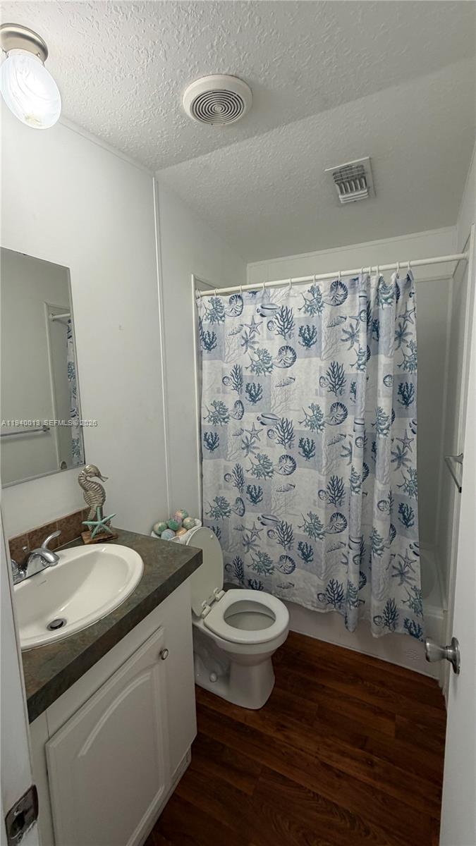 25345 Southwest 129th Place Homestead, FL 33032 - Photo 4 of 35 a bathroom with a granite countertop toilet a sink a mirror and a shower