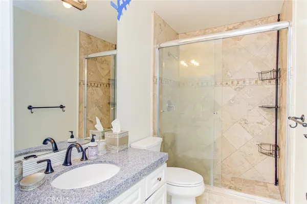 a bathroom with a granite countertop sink toilet a mirror and shower
