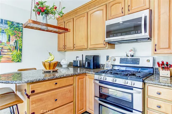 a kitchen with granite countertop stainless steel appliances a stove a sink and a microwave