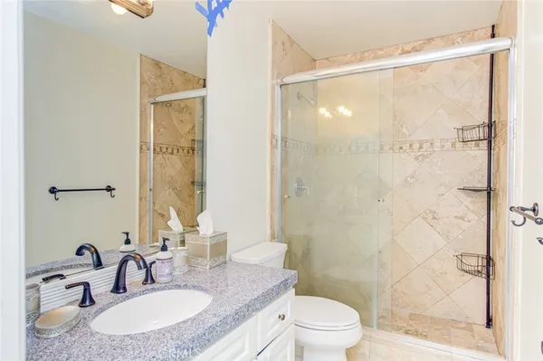 a bathroom with a granite countertop sink toilet a mirror and shower