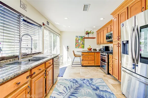 a large kitchen with stainless steel appliances kitchen island granite countertop a refrigerator and a sink