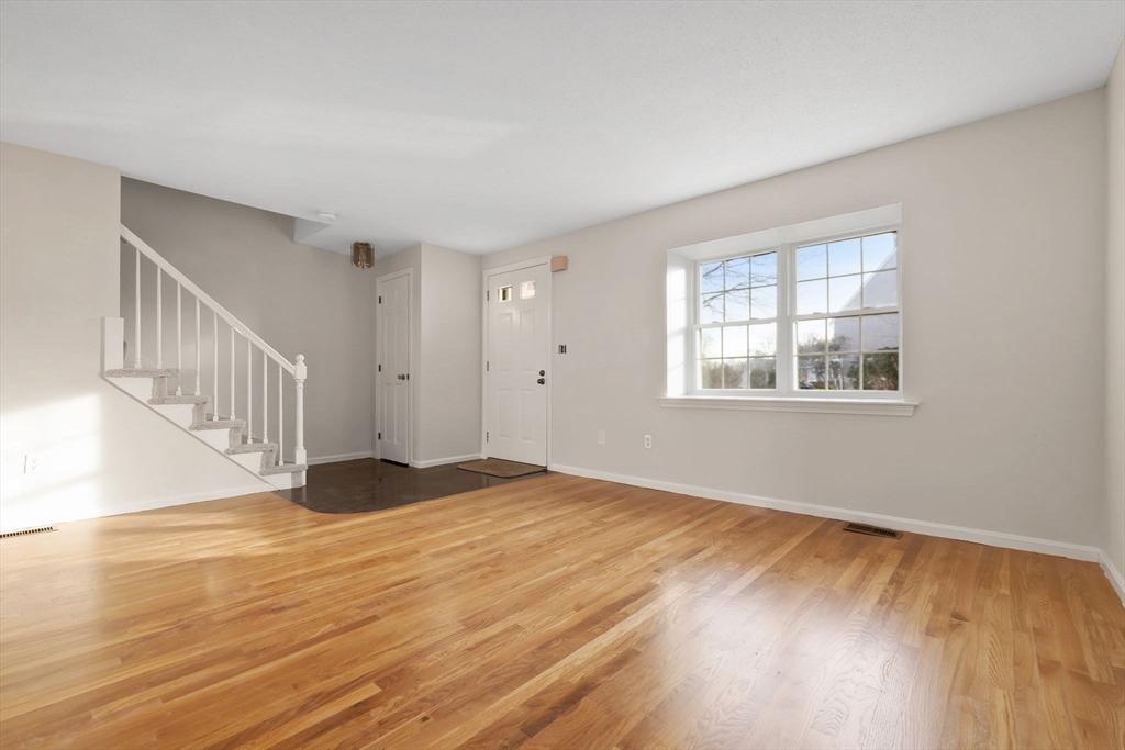 320 Newbury Street, Unit 304 Danvers, MA 01923 - Photo 11 of 32 a view of an empty room with wooden floor and a window