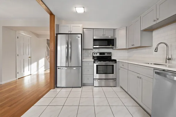 a kitchen with granite countertop a refrigerator and a stove top oven