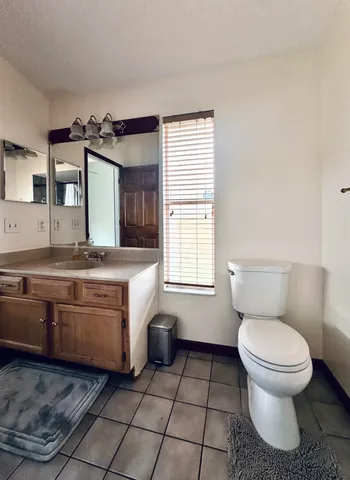 a bathroom with a granite countertop sink toilet and mirror