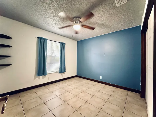 an empty room with windows and fan