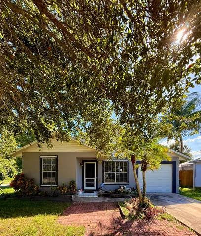 a front view of house with yard and trees in the background
