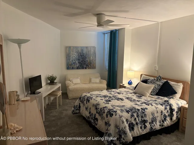 a bedroom with a bed a couch and a flat tv screen on the dresser