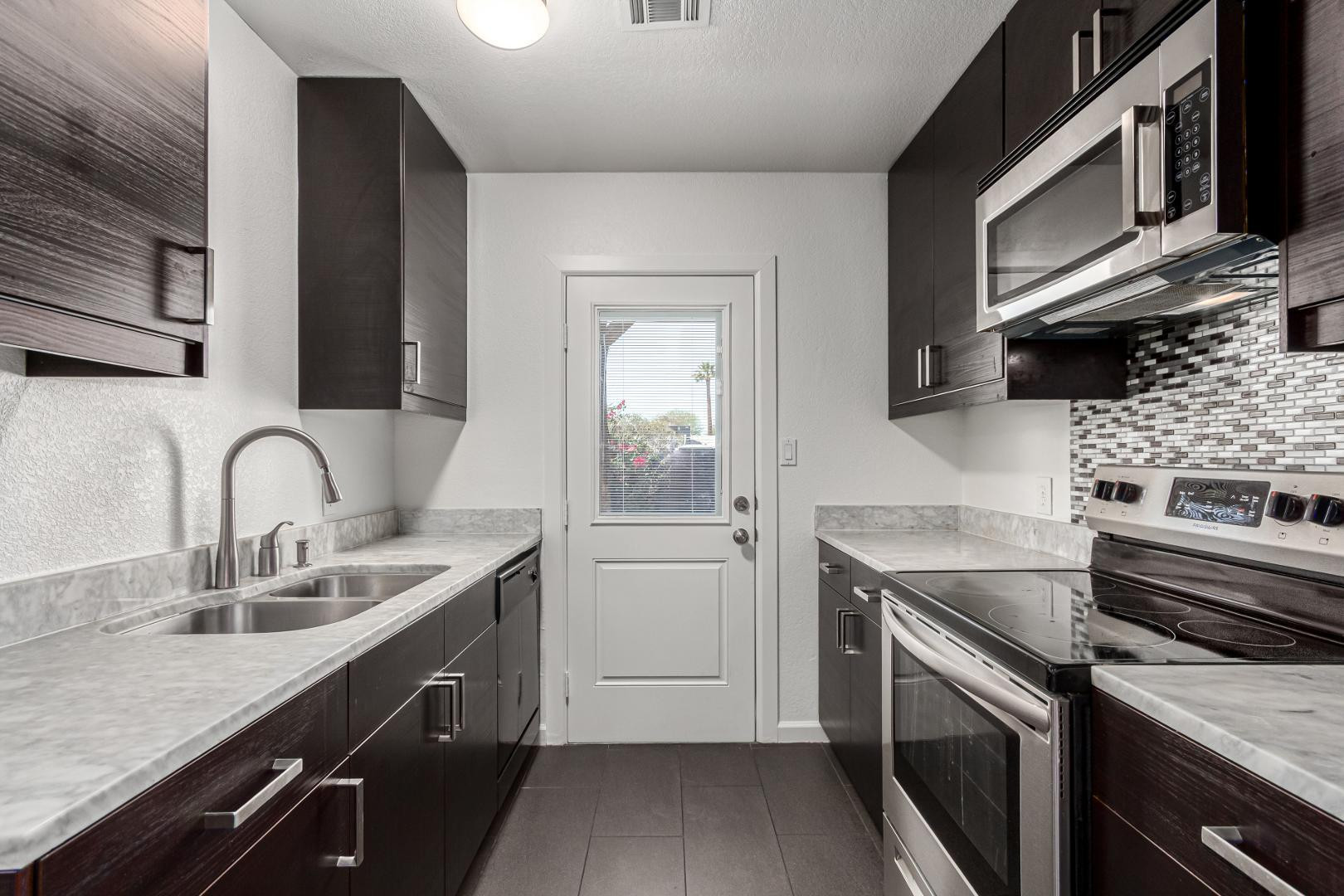 3034 North 35th Street, Unit 3 Phoenix, AZ 85018 - Photo 4 of 10 a kitchen with stainless steel appliances granite countertop a sink dishwasher stove and microwave with wooden cabinets