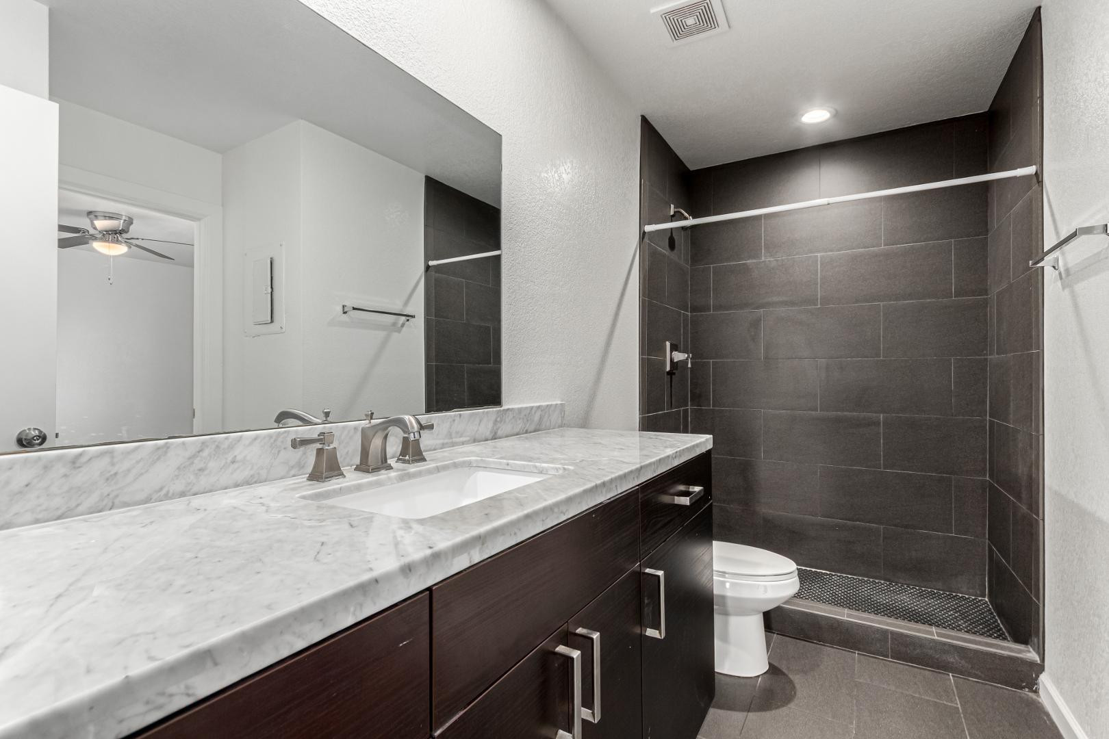 3034 North 35th Street, Unit 3 Phoenix, AZ 85018 - Photo 8 of 10 a bathroom with a granite countertop sink a toilet a mirror and shower