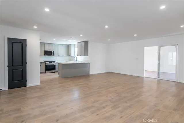 a view of an empty room with a kitchen and a window
