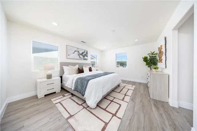 a spacious bedroom with a bed and wooden floor