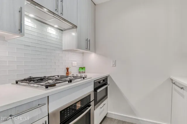 a kitchen with granite countertop a stove and a white cabinets