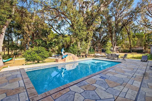 a view of a backyard with table and chairs potted plants and tree