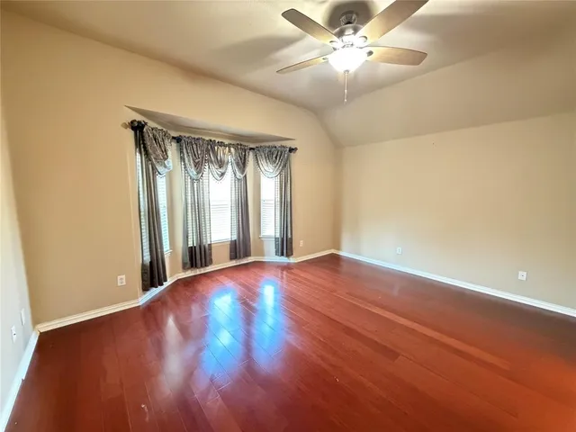 a view of an empty room with window and chandelier fan