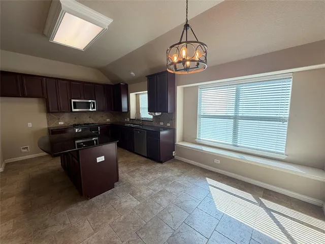 a large kitchen with granite countertop a stove and cabinets