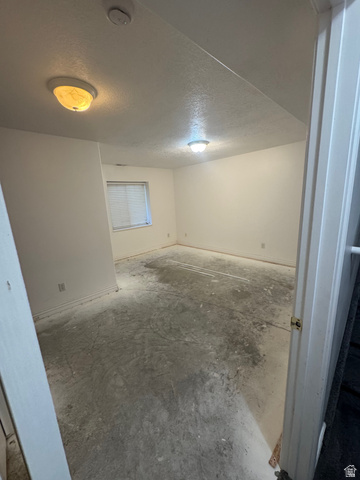 1976 River Bottom Road Springville, UT 84663 - Photo 42 of 45 Spacious room featuring a window with blinds, two ceiling-mounted light fixtures, white baseboards, and a concrete floor