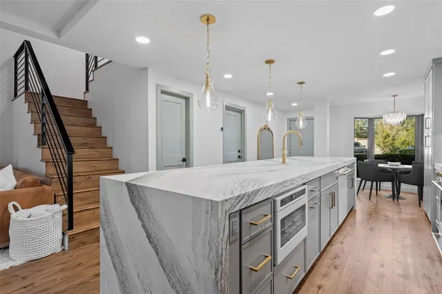 a large kitchen with kitchen island a stove a sink a dining table and chairs