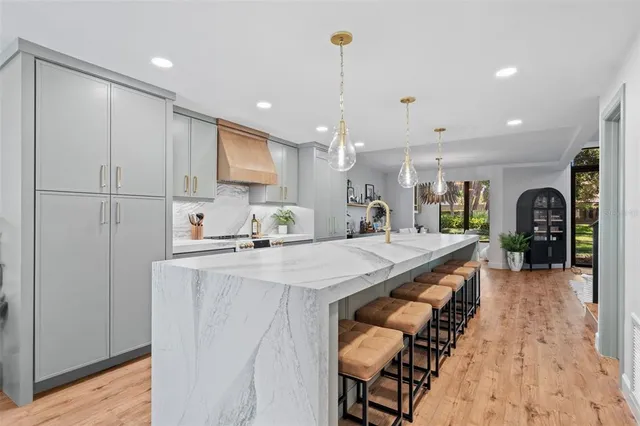 a large kitchen with kitchen island a stove a sink a refrigerator and a dining table with wooden floor