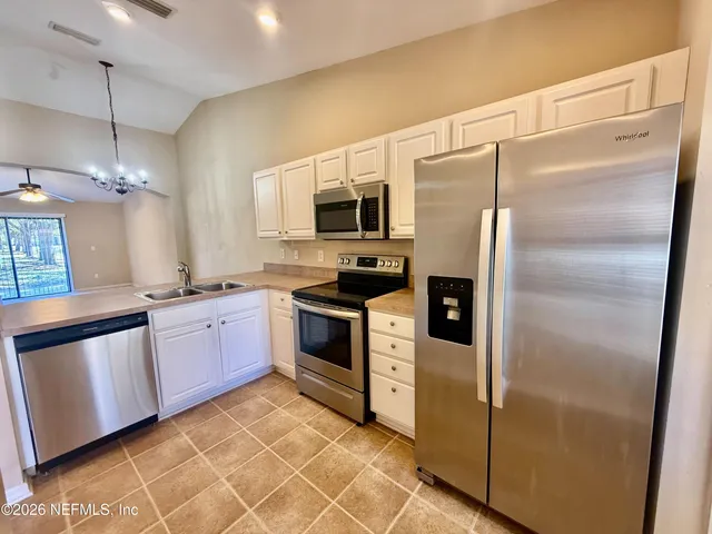 a kitchen with granite countertop a refrigerator a sink and dishwasher