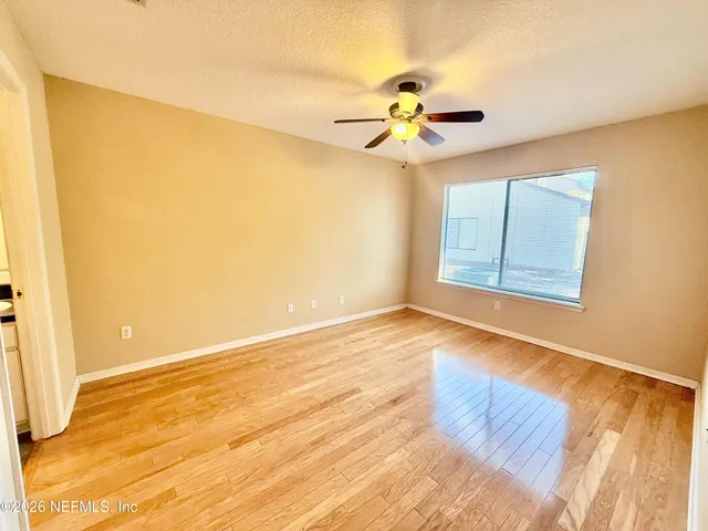 a view of an empty room with wooden floor and a window