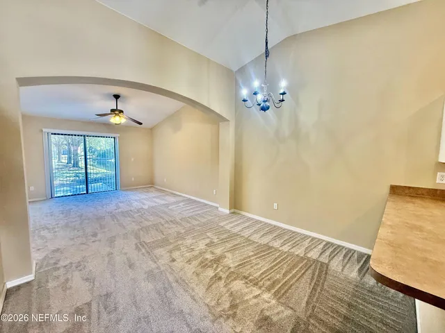 a view of a livingroom with a chandelier fan and windows
