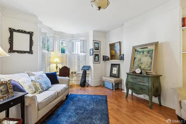 a living room with furniture kitchen view and a wooden floor