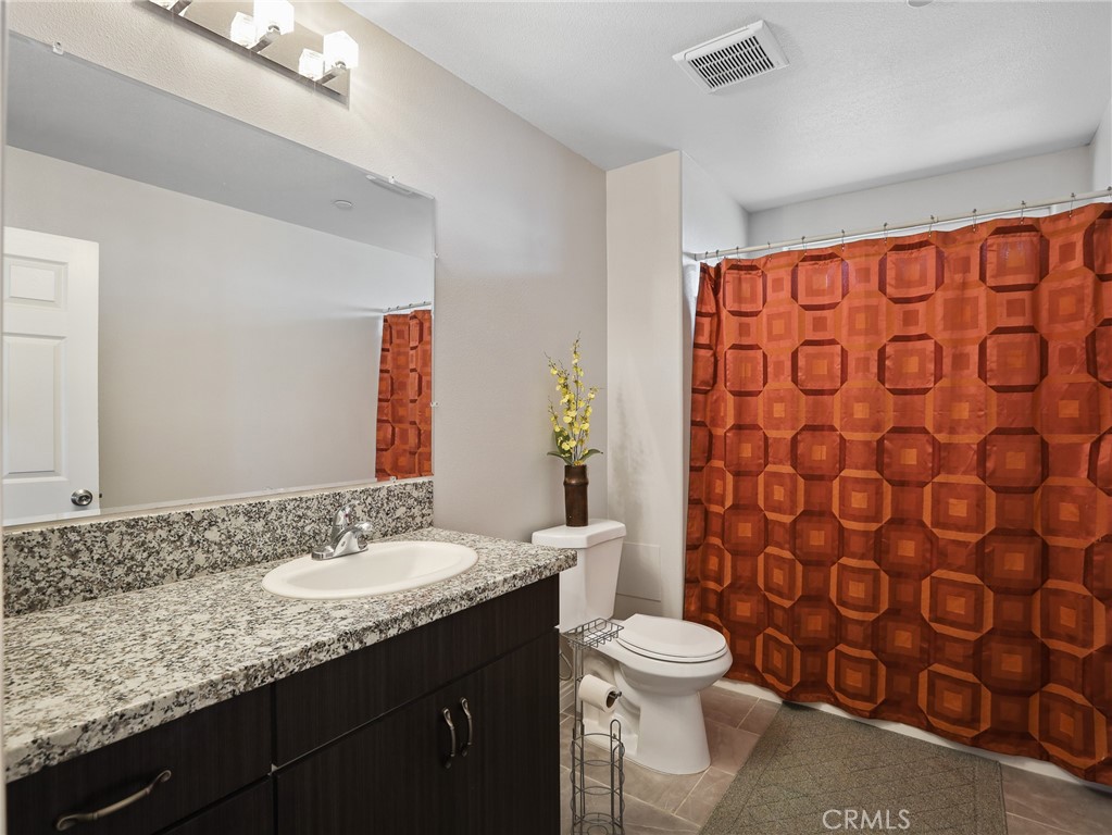 7755 7th Street Phelan, CA 92371 - Photo 12 of 27 a bathroom with a granite countertop sink a toilet and a shower