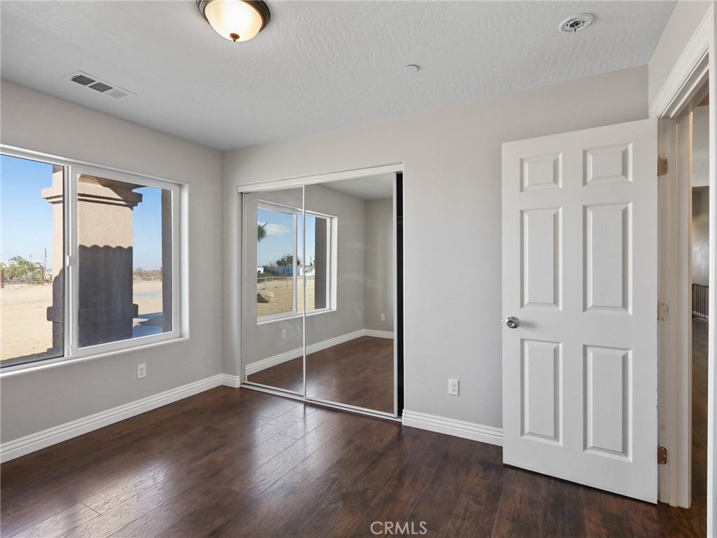 7755 7th Street Phelan, CA 92371 - Photo 13 of 27 an empty room with wooden floor and windows