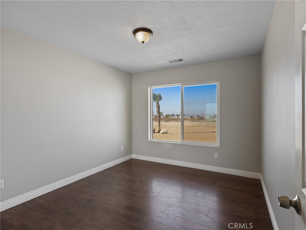 7755 7th Street Phelan, CA 92371 - Photo 15 of 27 an empty room with wooden floor and windows