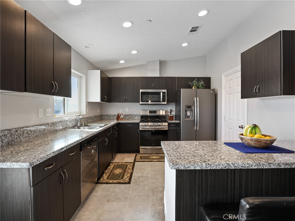 7755 7th Street Phelan, CA 92371 - Photo 6 of 27 a kitchen with granite countertop kitchen island stainless steel appliances a sink stove top oven and refrigerator