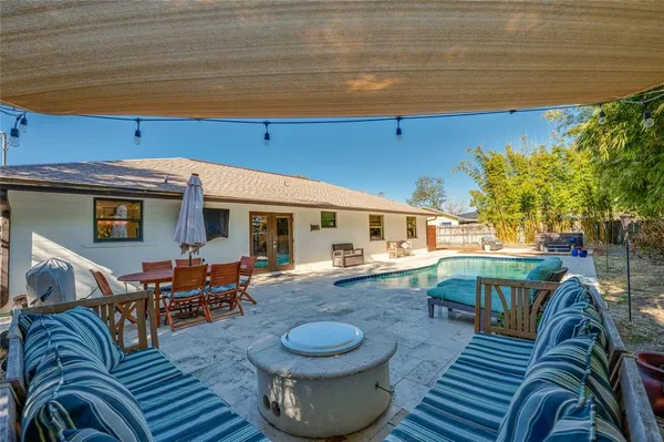 a backyard of a house with table and chairs plants and large trees