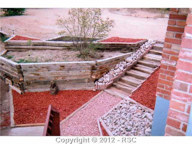 6980 Baker Road Colorado Springs, CO 80908 - Photo 6 of 25 Nicely Landscaped with Stairs From Deck and Parking Area Providing Access To The Front or Back