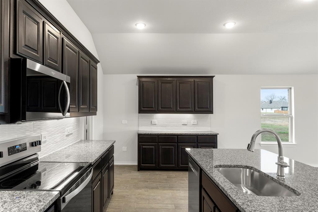 1120 Rushing Court Aubrey, TX 76227 - Photo 5 of 27 a kitchen with stainless steel appliances a sink a stove and microwave