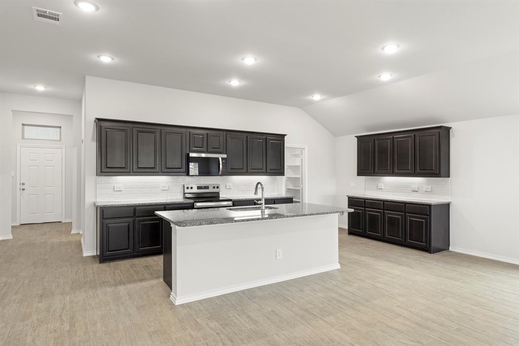 1120 Rushing Court Aubrey, TX 76227 - Photo 6 of 27 a large kitchen with stainless steel appliances a stove a sink and a refrigerator
