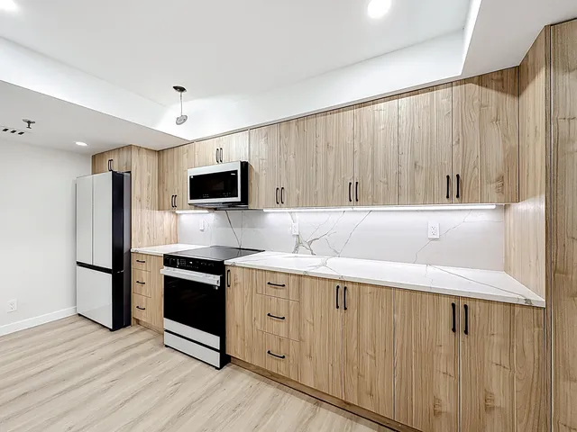 a view of a kitchen with a sink and wooden cabinets